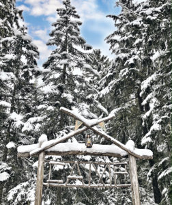 Snowmobile Safari in Whistler and wooden Base Camp sign among snow covered pine trees.